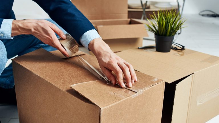 Image of person on suit taping up packing box